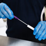 Close-up of a healthcare worker wearing blue gloves performing an ATP surface swab test to assess cleanliness and detect potential contamination.