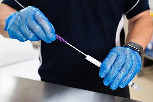 Close-up of a healthcare worker wearing blue gloves performing an ATP surface swab test to assess cleanliness and detect potential contamination.