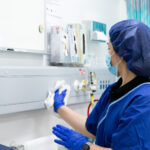 Healthcare cleaner disinfecting high-touch surfaces around a patient care area, ensuring infection control compliance.