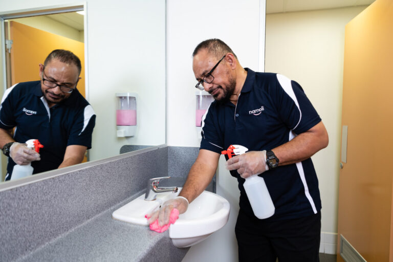 Namoli cleaning professional performing touch point cleaning on a high-contact bathroom surface using TGA-approved disinfectant.